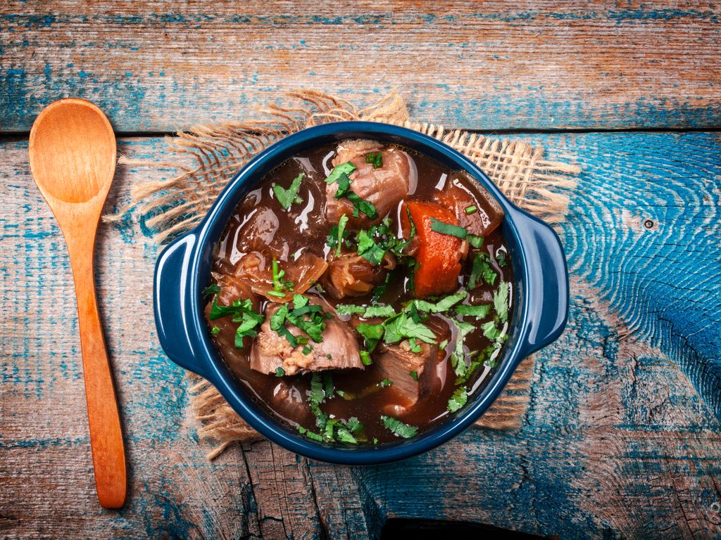 Daube de sanglier mijotée au vin rouge avec carottes et herbes fraîches, présentée en cocotte rustique.