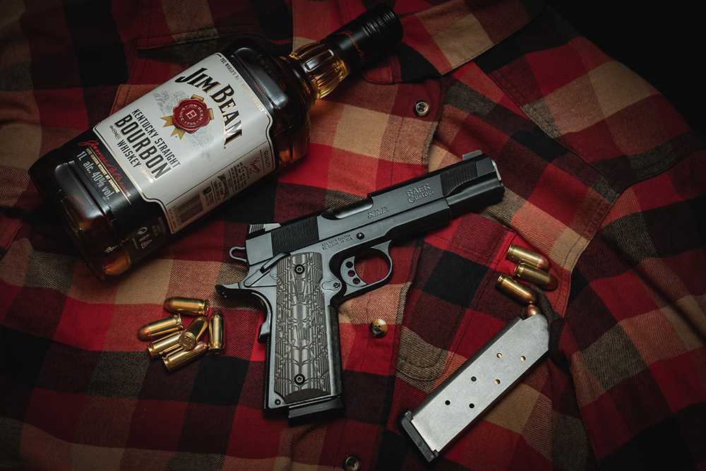 Pistolet custom 1911 accompagné d’une bouteille de bourbon américain Jim Beam